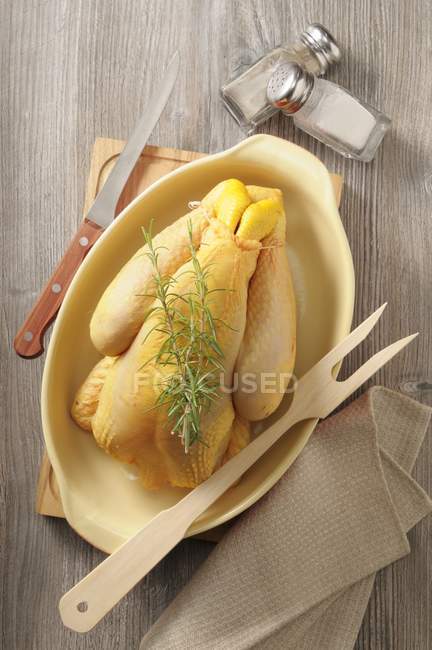 Вид сверху на сырую курицу с розмарином на выпечке блюдо с вилкой — стоковое фото