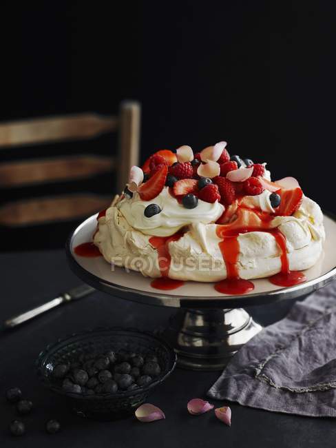 Closeup view of Pavlova with strawberries, blueberries and rose petals — Stock Photo