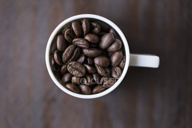 Granos de café en taza - foto de stock