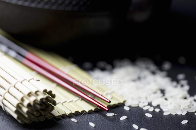 Chopsticks, bamboo mat and rice — Stock Photo