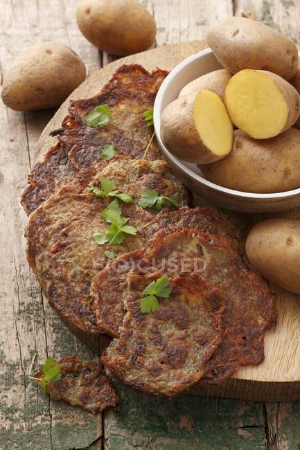 Potato cakes and fresh potatoes — Stock Photo