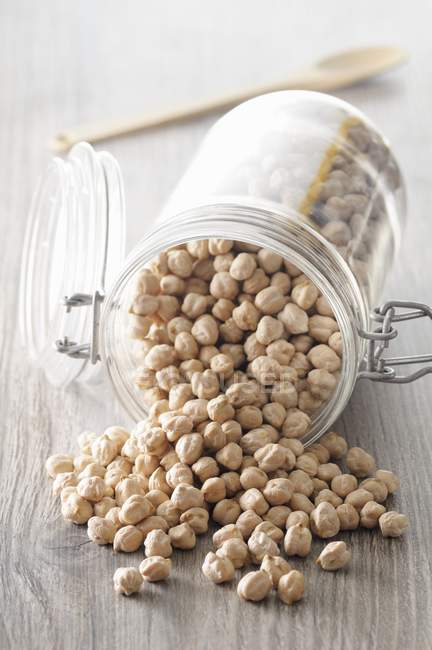 Closeup view of chickpeas in overturned glass jar — Stock Photo