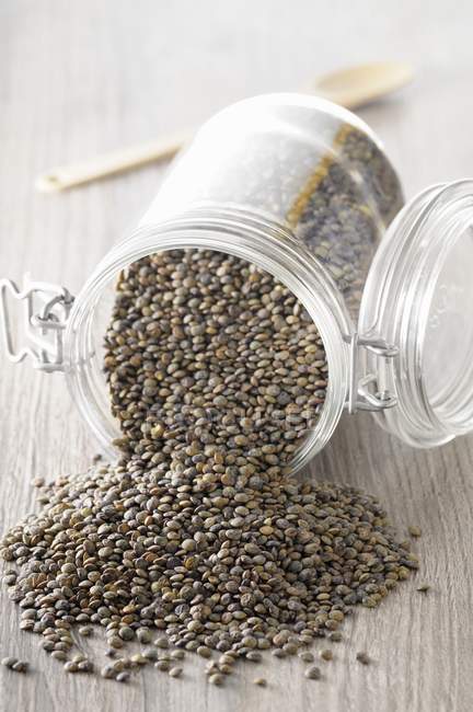 Elevated view of lentils and overturned jar on wooden surface — Stock Photo