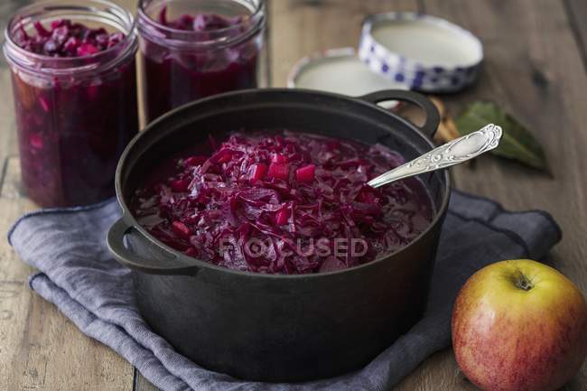 Apple red cabbage in a pot with spoon over towel on table — Stock Photo