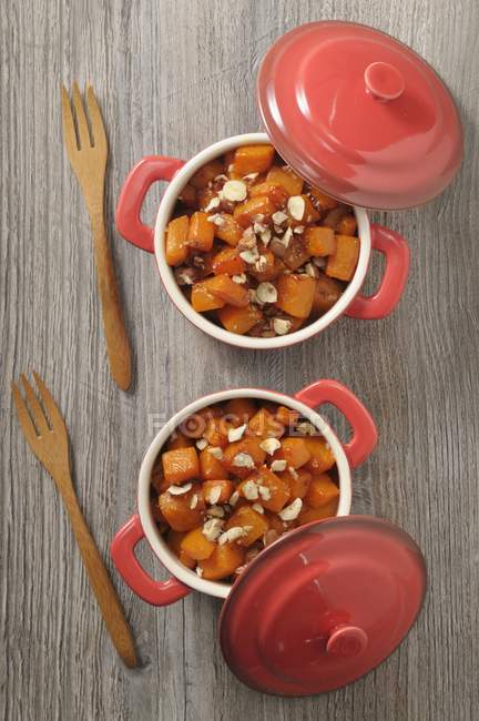 Butternut squash bake with hazelnuts in pots over wooden surface — Stock Photo