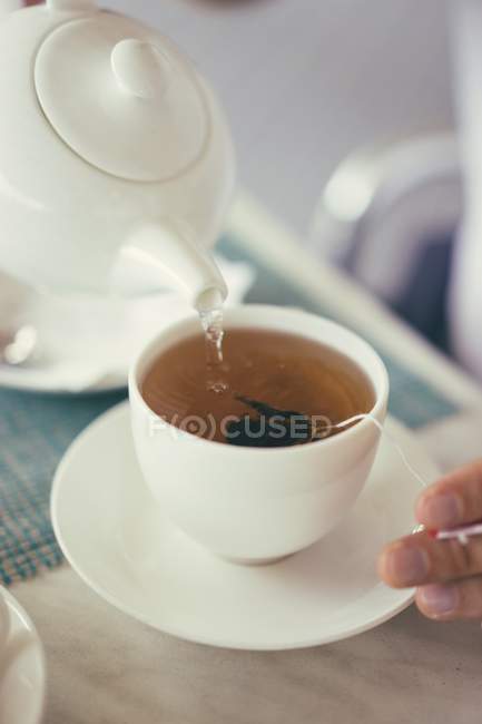 Pouring tea into cup — Stock Photo