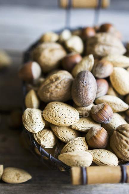 Vue rapprochée de noix mélangées dans un panier sur une surface en bois rustique — Photo de stock
