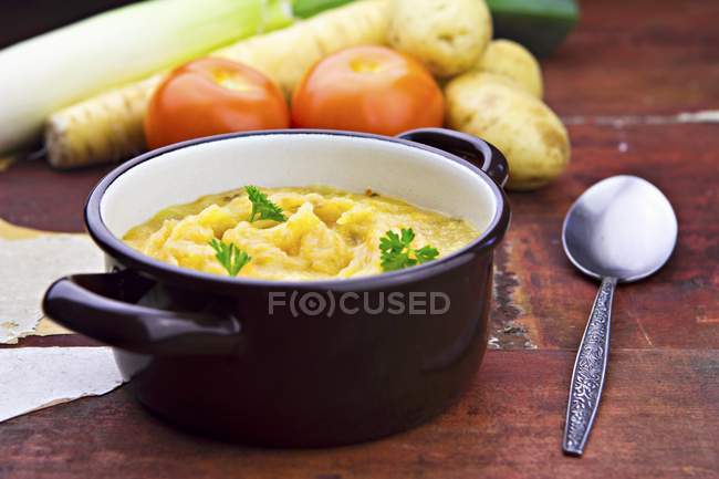 Thick cream of vegetable soup in pot  over wooden surface with spoon — Stock Photo