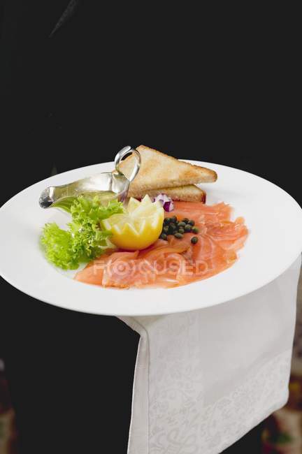 Closeup view of Gravad lax with toast triangles, lemon and salad leaf — Stock Photo