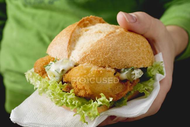 Mão segurando hambúrguer de peixe — Fotografia de Stock