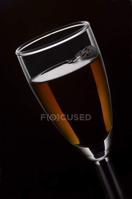 Vista de primer plano de vidrio con bebida sobre fondo negro - foto de stock