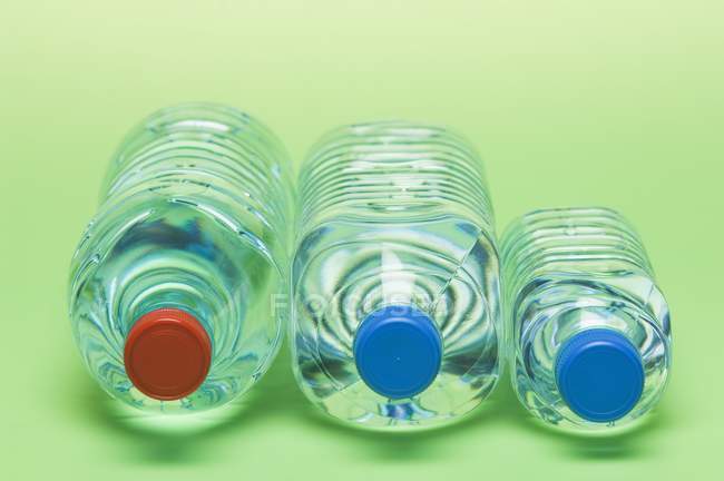 Крупним планом три пластикові пляшки води на зеленій поверхні — стокове фото