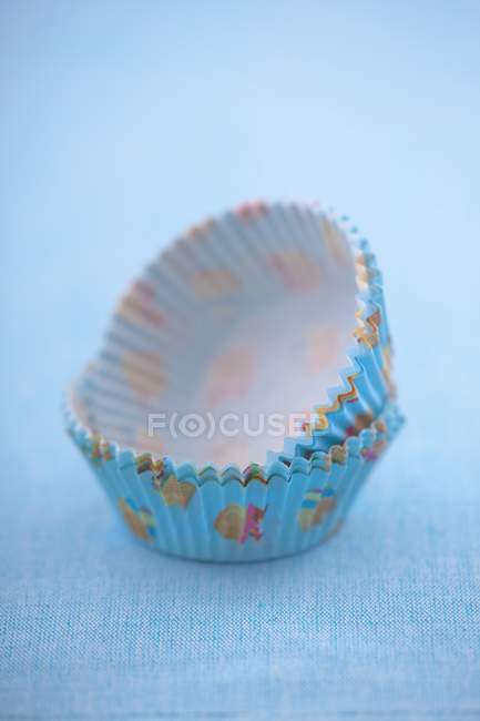 Vista close-up de casos de muffin de papel na superfície azul — Fotografia de Stock