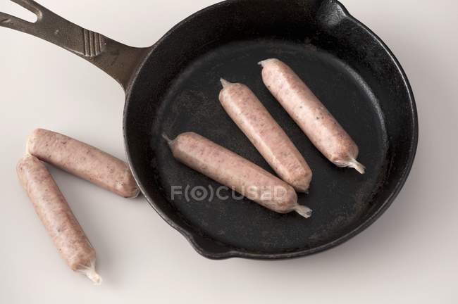 Невареные колбаски с железной сковородой — стоковое фото