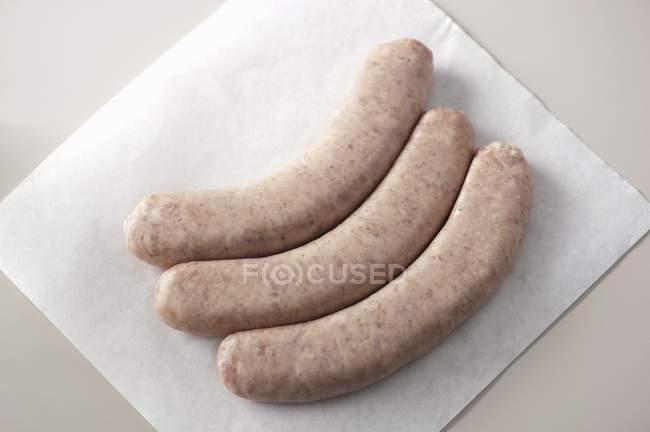 Closeup top view of three Bratwurst sausages on white paper — Stock Photo