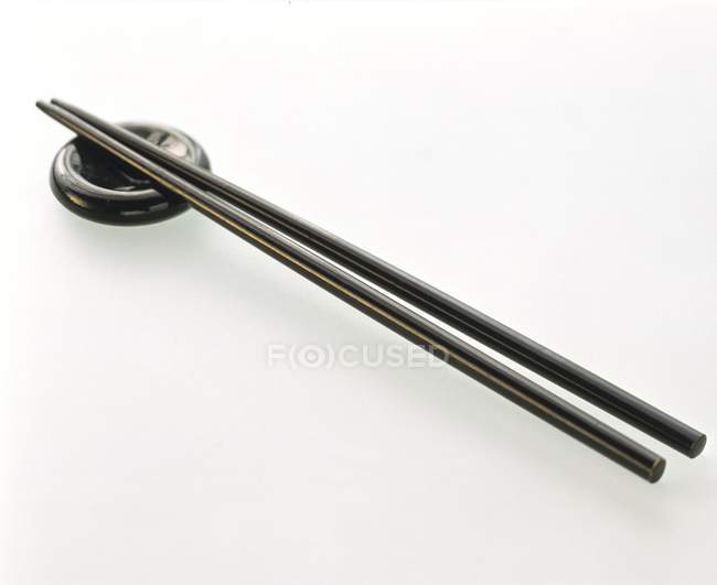 Closeup view of two black chopsticks with holder on white surface — Stock Photo
