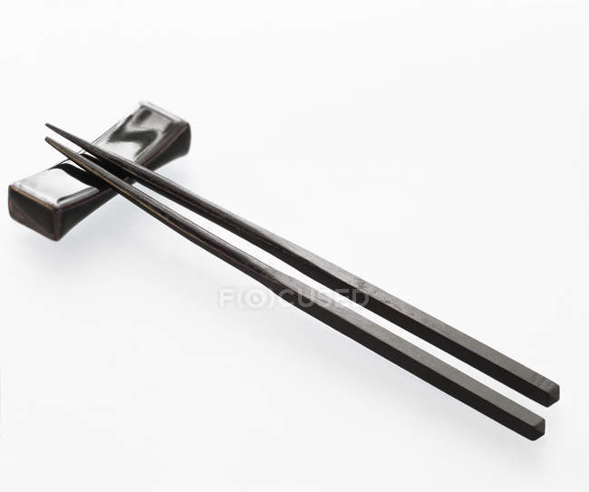 Closeup view of two black chopsticks with holder on white background — Stock Photo