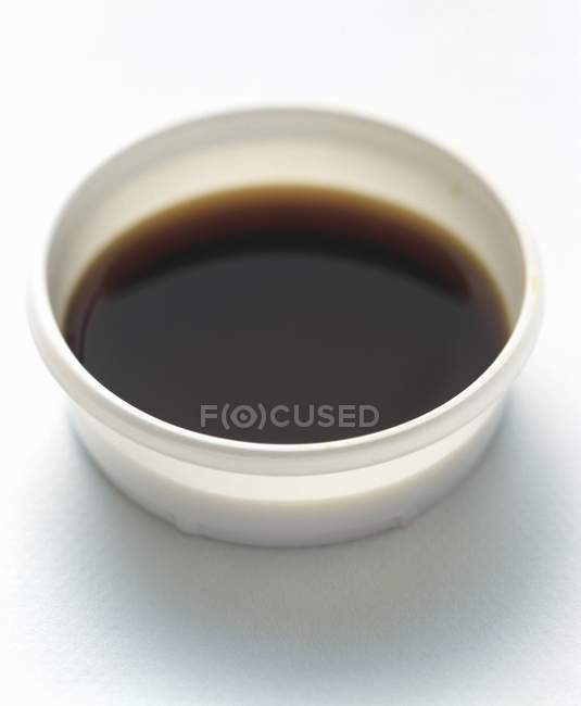 Closeup view of soy sauce in a white plastic container — Stock Photo