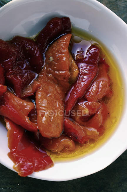 Peperoni rossi marinati con olio d'oliva in piatto bianco — Foto stock