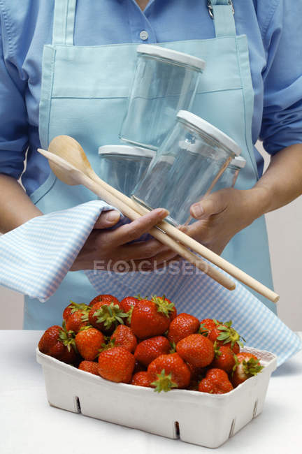 Woman standing with jars and strawberries — Stock Photo