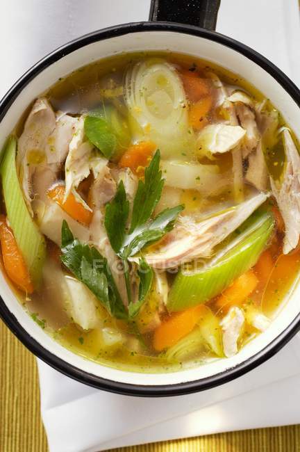 Куриный суп с овощами в кастрюле над полотенцем — стоковое фото