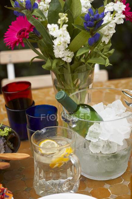 Vue élevée du vin blanc avec de l'eau de citron, des fleurs et des verres sur la table — Photo de stock