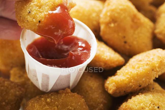 Dipping chicken nugget in ketchup — Stock Photo