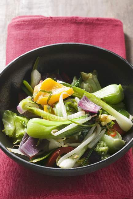 Verduras en wok sobre toalla roja - foto de stock