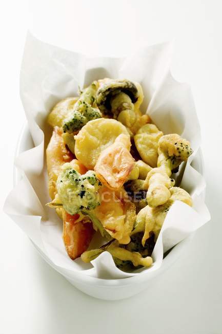 Frittiertes Gemüse in weißer Schale mit Papier auf weißem Hintergrund — Stockfoto