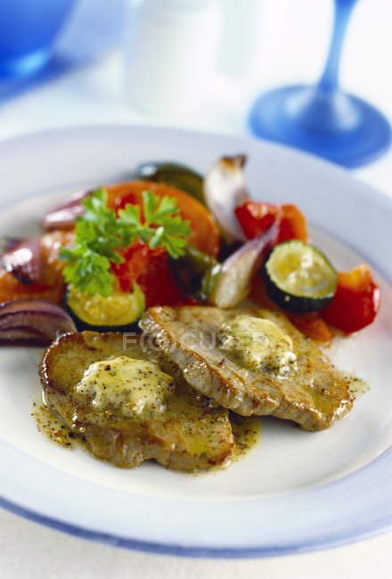 Closeup view of pork steaks with herb butter and vegetables — Stock Photo