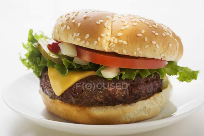Cheeseburger with tomato and gherkin — Stock Photo
