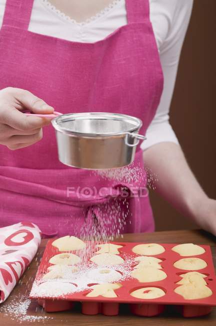 Vista ritagliata di donna spruzzando zucchero a velo sopra cottura fresca — Foto stock