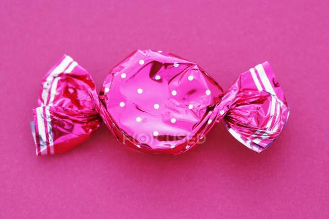 Крупный план конфет в пунктирной обертке на розовом фоне — стоковое фото