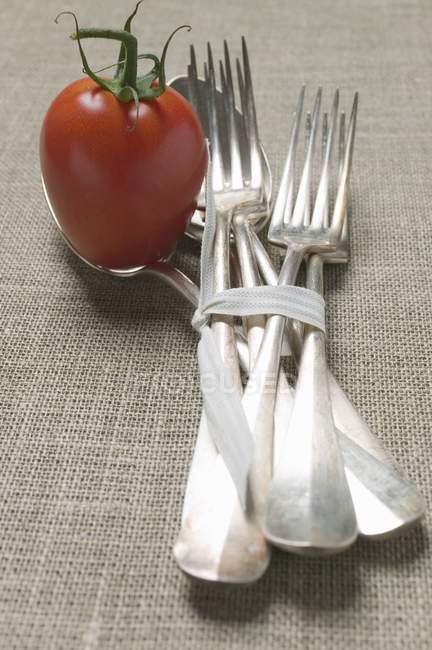 Tomato with tied forks and spoons — Stock Photo
