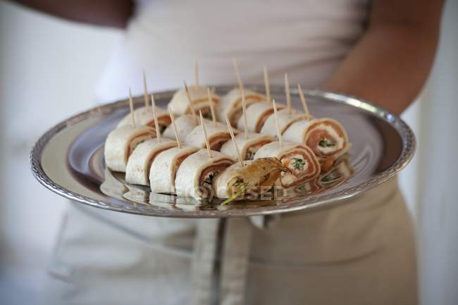 Waitress serving crepe rolls filled with salmon — Stock Photo