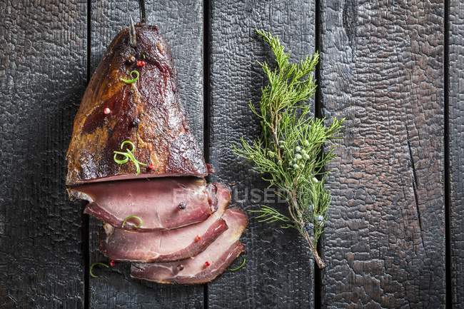 Sliced Smoked ham with sprig of juniper — Stock Photo