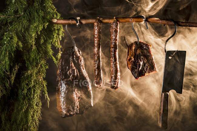 Closeup view of hanged ham, bacon and sausages in a smoking chamber — Stock Photo