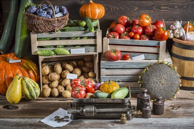 Овощи и сливы на рынке с коробками и ящиками — стоковое фото