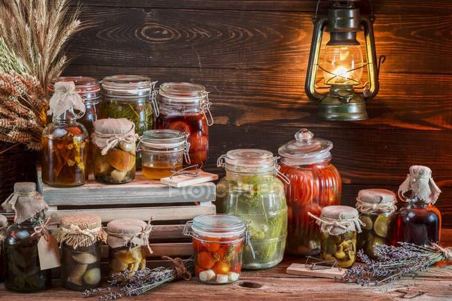 Divers bocaux de champignons et légumes conservés sur fond de bois — Photo de stock