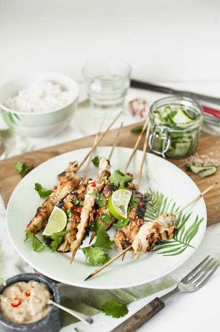 Closeup view of Satay skewers with coriander and limes — Stock Photo