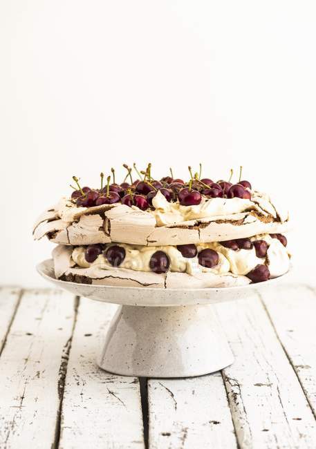Vista de primer plano de la torta Pavlova con cerezas en el stand - foto de stock