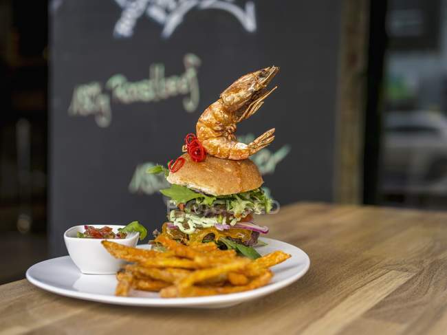 Burger with prawn on top and fries — Stock Photo