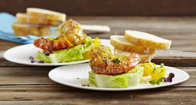 Cos lettuce with prawns on white plates over wooden surface — Stock Photo