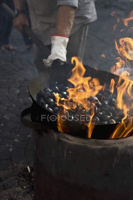 Visão cortada da pessoa que frita castanhas em uma grande panela — Fotografia de Stock