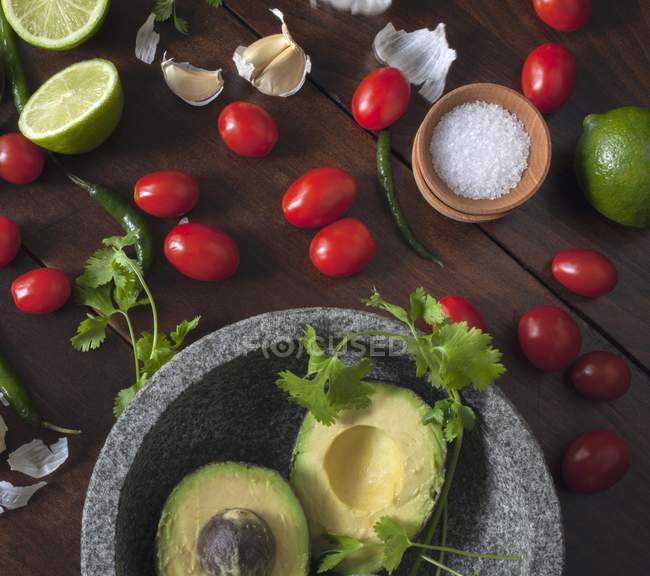 Інгредієнти для гуакамоле в кам'яній мисці над столом — стокове фото