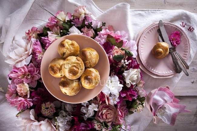 Top view of Brioches on plate and colorful flower wreath — Stock Photo