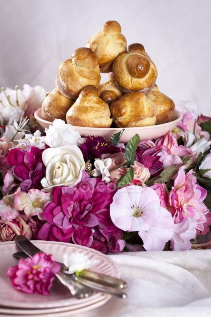 Closeup view of Brioches heap on plate and flowers — Stock Photo