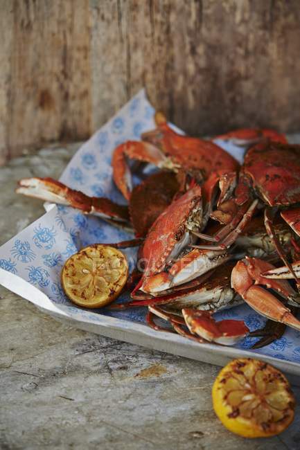 Crabes cuits avec des moitiés de citron sur un plateau de service — Photo de stock