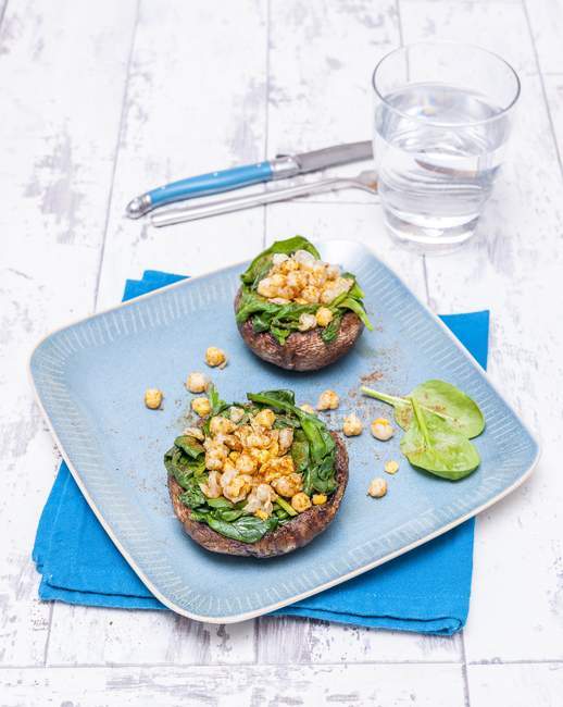 Funghi portobello ripieni di spinaci e ceci su piatto blu — Foto stock