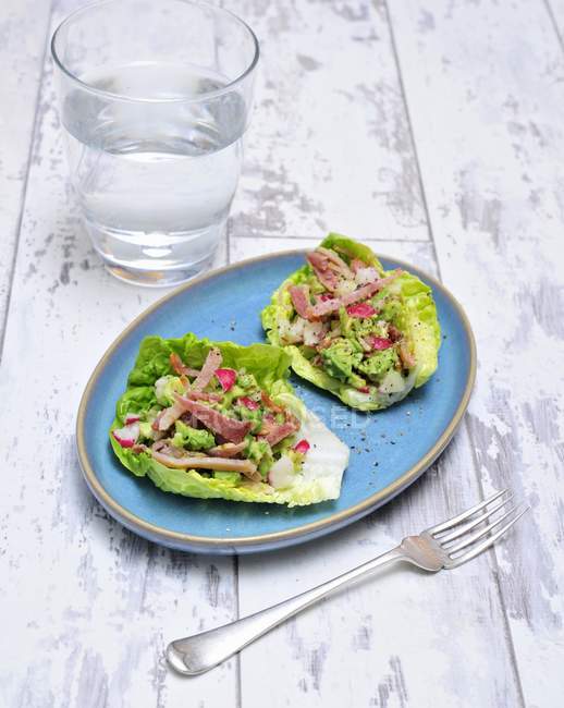 Avocado mit Speck und Radieschen auf Salatblättern auf Holzoberfläche — Stockfoto